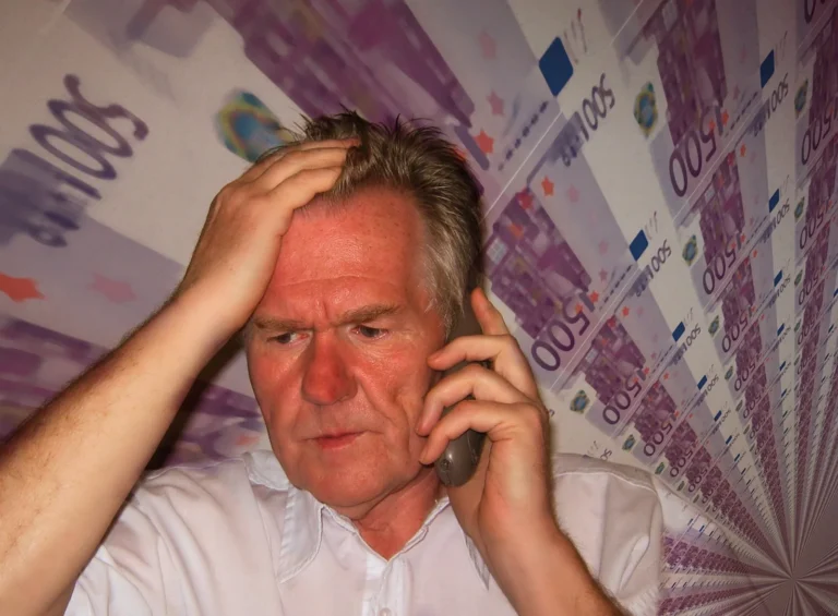 Zmartwiony mężczyzna rozmawia przez telefon z oszustem