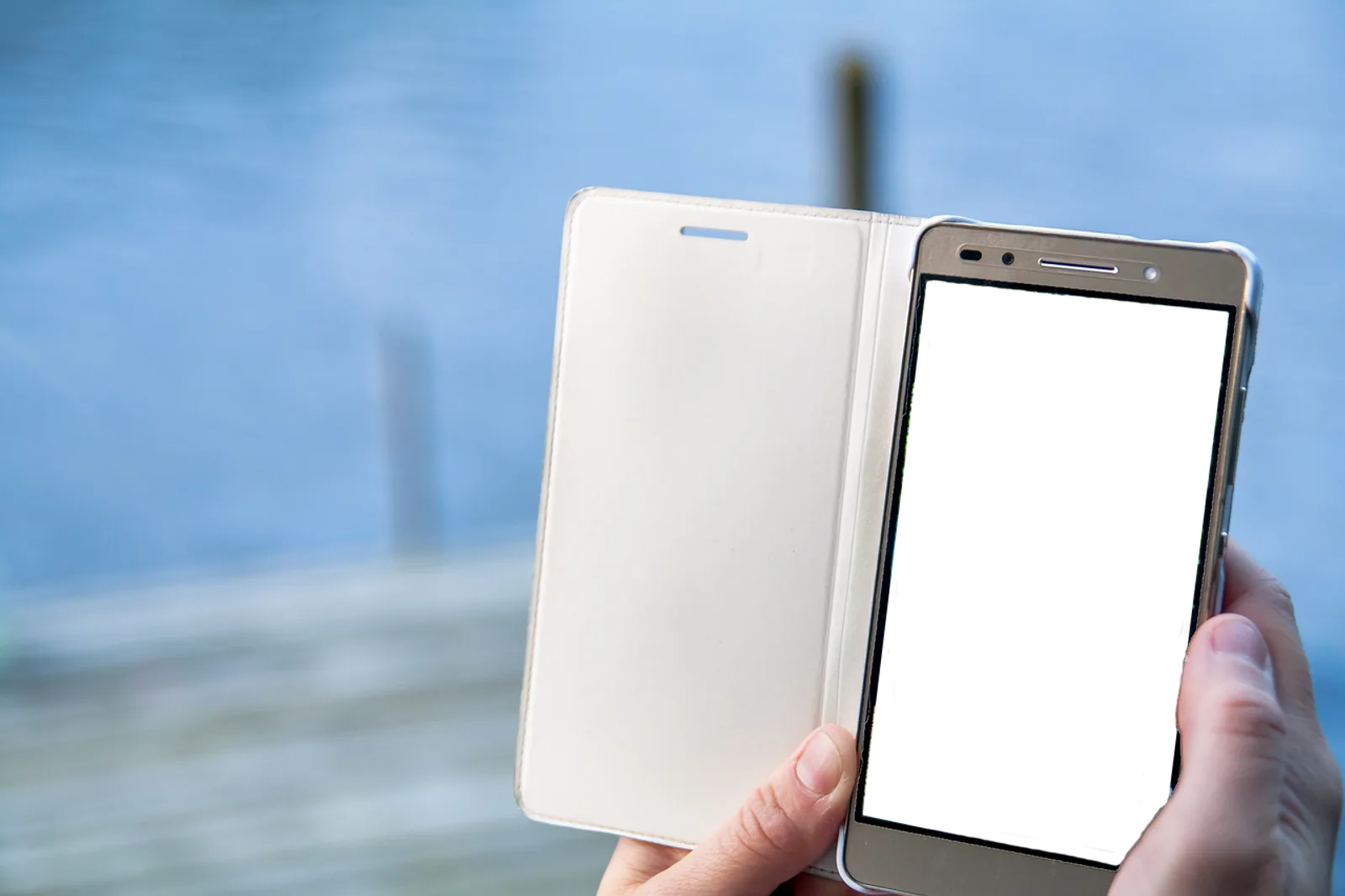 Dłoń trzymająca smartfon w otwartym etui z pustym ekranem