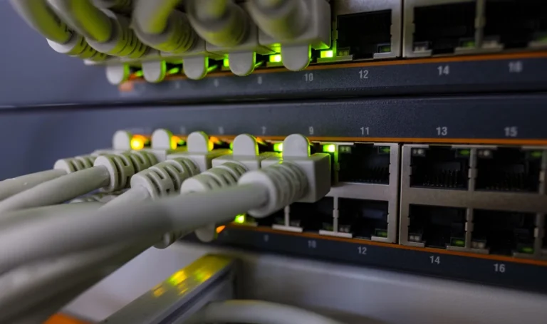 Kable sieciowe podłączone do przełącznika z zapalonymi diodami